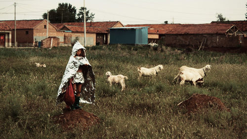 Boy standing on field by building