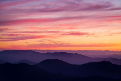 Scenic view of silhouette mountains against romantic sky at sunset