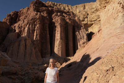 Senior woman standing against rock formation