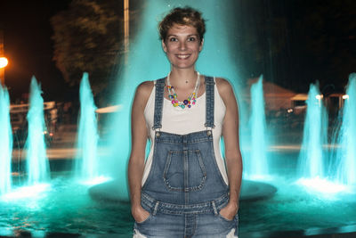 Portrait of woman against blue waterfall at night