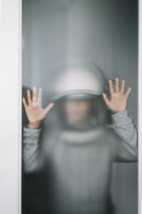 Busybody kid with helmet looking through the crack in the door with funny annoyed expression