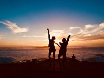 Silhouette people at beach against sky during sunset