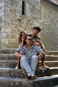 Portrait of friends sitting on staircase outdoors