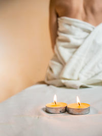 Two aroma candles in a massage room,back of a woman who is sitting on a massage table