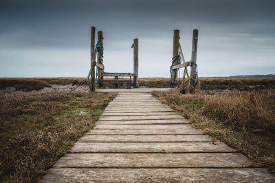 Boardwalk on field against sky