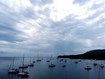 Boats in sea against cloudy sky