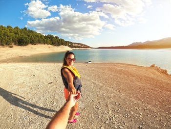 Portrait of smiling young woman on beach against sky