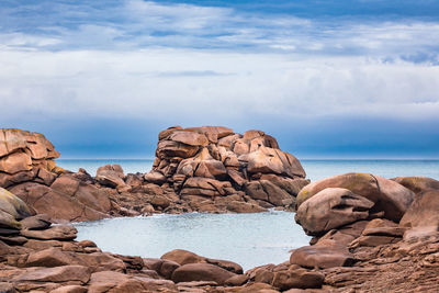 Rock formations by sea against sky