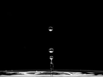Close-up of water drop splashing against black background