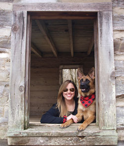 Portrait of smiling woman with dog at window