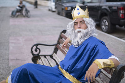 Portrait of man in costume sitting on bench