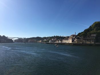 Scenic view of sea by buildings against clear blue sky