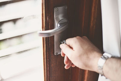 Close-up of hand holding metal door