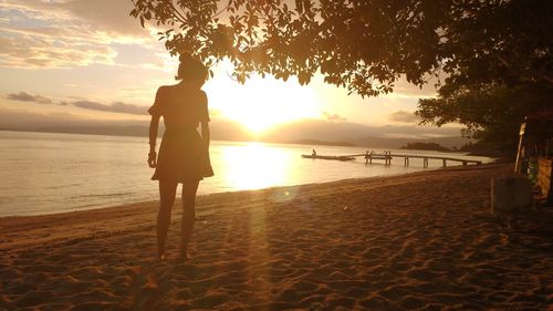 Silhouette man standing on beach against sunset sky