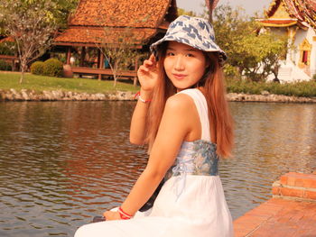 Portrait of smiling young woman standing against lake