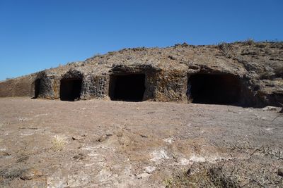 Built structure on landscape against clear blue sky