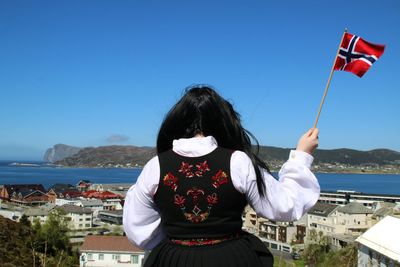 Woman standing by sea against clear blue sky