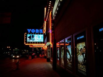 Exterior of illuminated movie theater by footpath at night