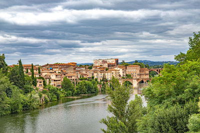 Buildings by river against sky