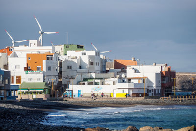 Traditional windmill by sea against sky