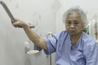 Side view of senior man holding hands in bathroom