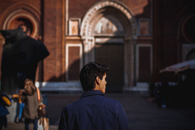 Rear view of men outside temple against building