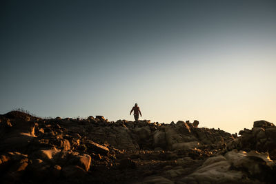 Man standing on rock against sky