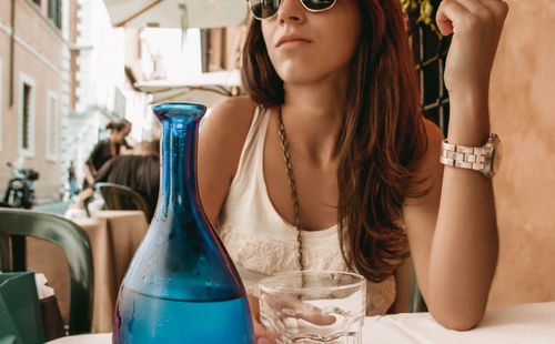 Midsection of mid adult woman with drinking glass on table at outdoor cafe