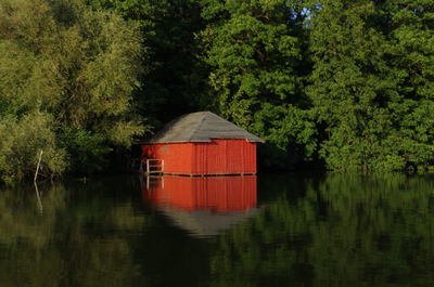 House by lake against trees