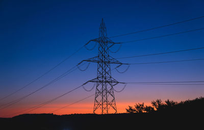 Low angle view of silhouette electricity pylon against sky at sunset