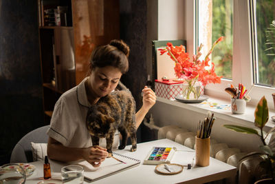 Female painter artist making an abstract watercolor painting. painting with cat