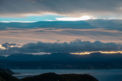 Scenic view of sea and mountains against dramatic sky