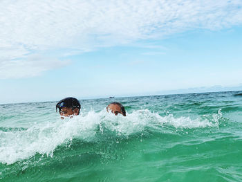 People in sea against sky