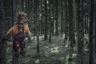Scarecrow hanging from tree in forest