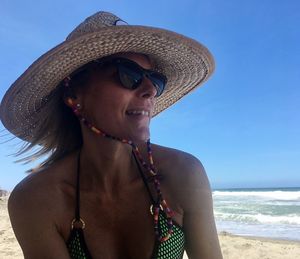 Young woman wearing hat on beach against sky