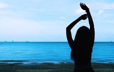 Woman standing at beach against sky