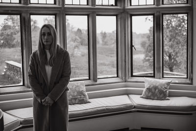 Portrait of young woman looking through window