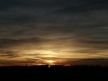 Silhouette landscape against dramatic sky during sunset