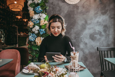 Full length of woman using phone on table