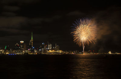 Firework display over illuminated buildings in city at night