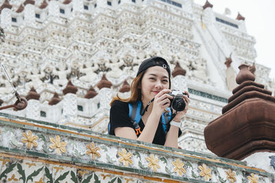 Low angle view of young woman photographing through camera