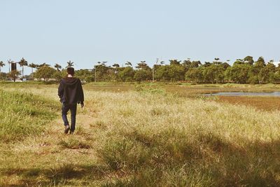 Full length of man standing on grassy field against clear sky