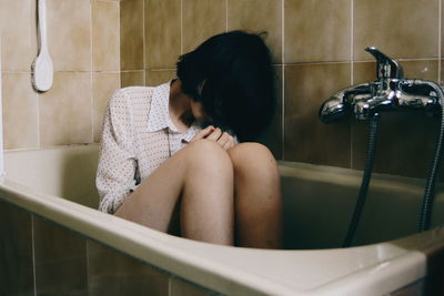 Woman sitting in bathtub at home
