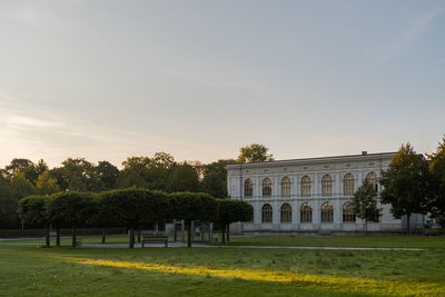 Lawn by building against sky at sunset