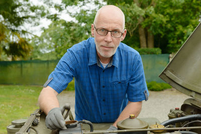 Portrait of mechanic repairing vehicle against trees