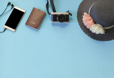 Close-up of hat by camera over blue background