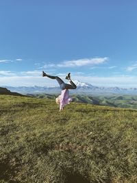 Woman with arms raised on field against sky