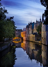 Bridge over canal amidst buildings in city against sky