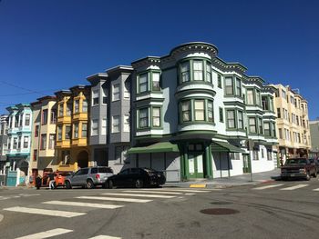 Cars on road by building against blue sky