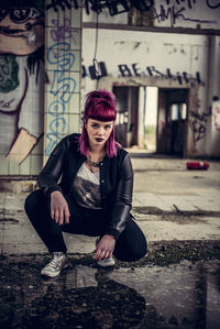 Portrait of young woman crouching in abandoned building